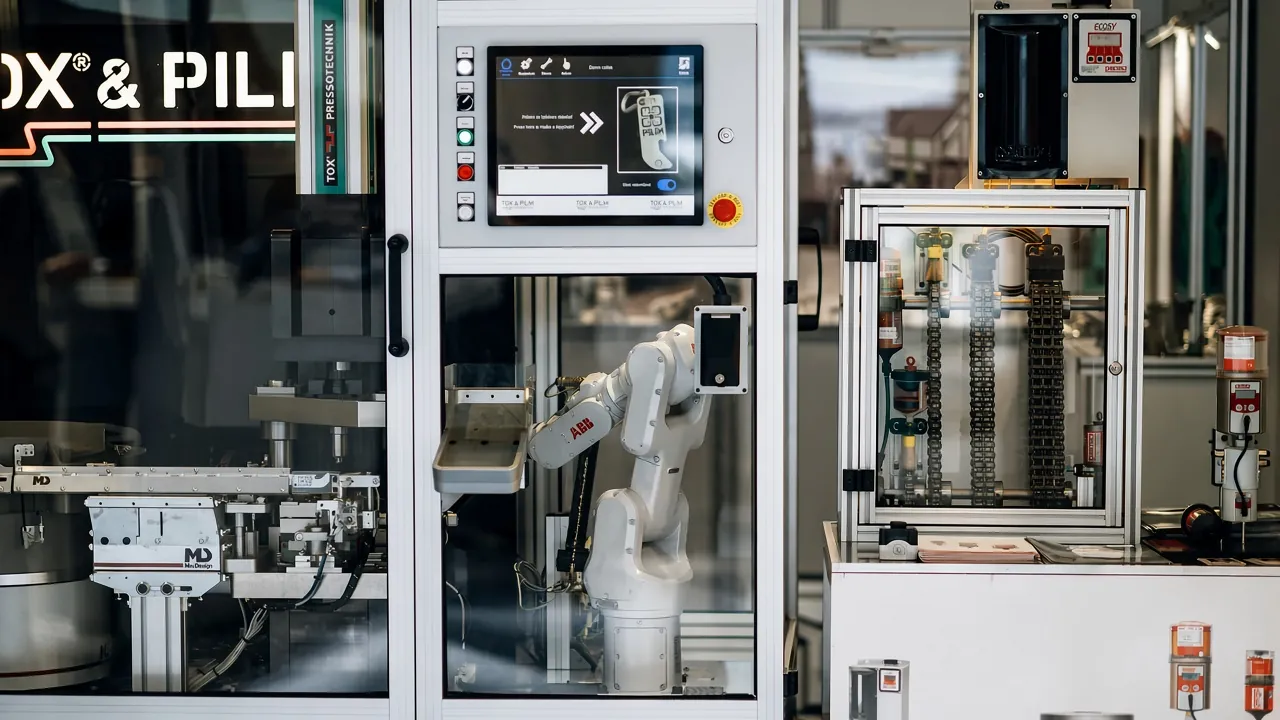 Robot arm operates machine in factory setting