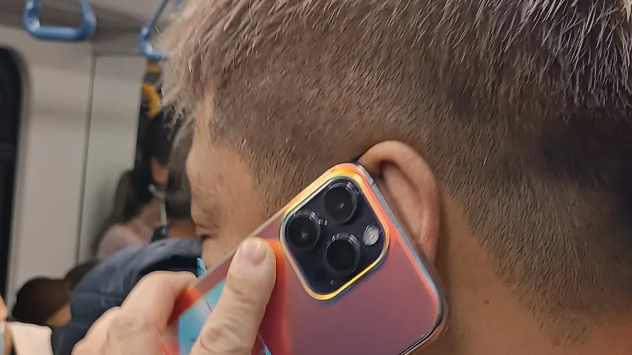 HK male hearing n talking smartphone in train January 2024 R12S 01