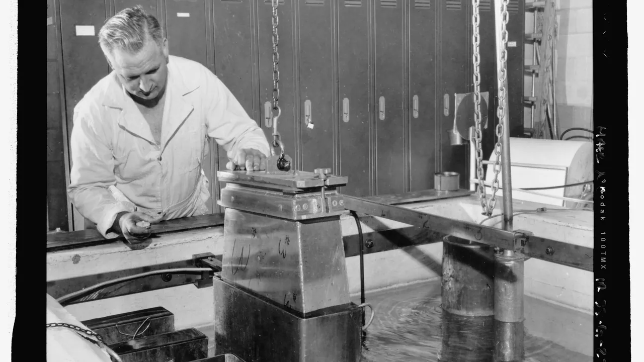 GAMMA FACILITY, TRA-611, INTERIOR. WITH HELP OF OVERHEAD CHAIN AND HOOK, SCIENTIST GUIDES METAL CONTAINER (HOLDING POTAT