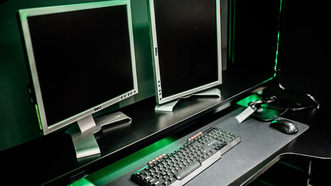 Dual monitor setup in a gaming room with keyboard and mouse in focus