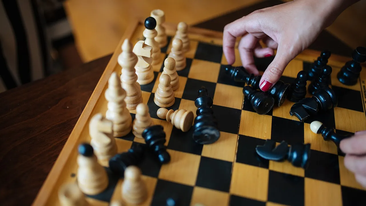 Skilled chess player making a strategic move during an indoor game with a wooden chess set