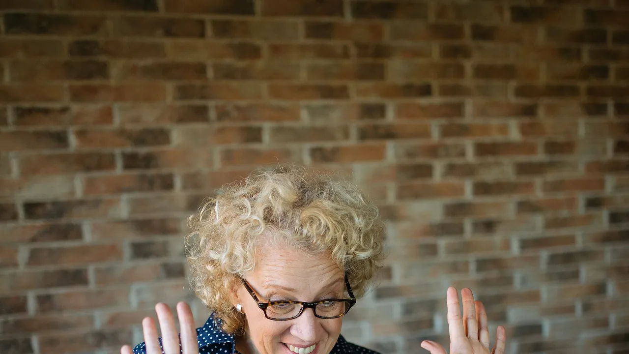 Cheerful woman smiling and making gestures with her hands while talking on a video call on her laptop