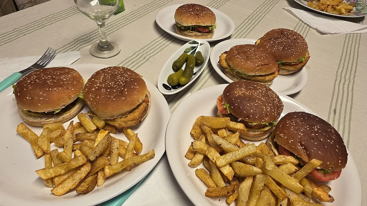 Full Argentine meal with hamburgers, chicken burger-style sandwiches, french fries, and pickled gherkins on a set dinner